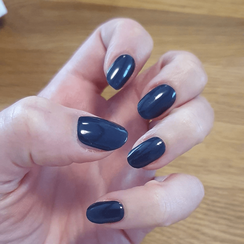 Navy blue non-UV nail wraps on hand displaying deep glossy finish manicure