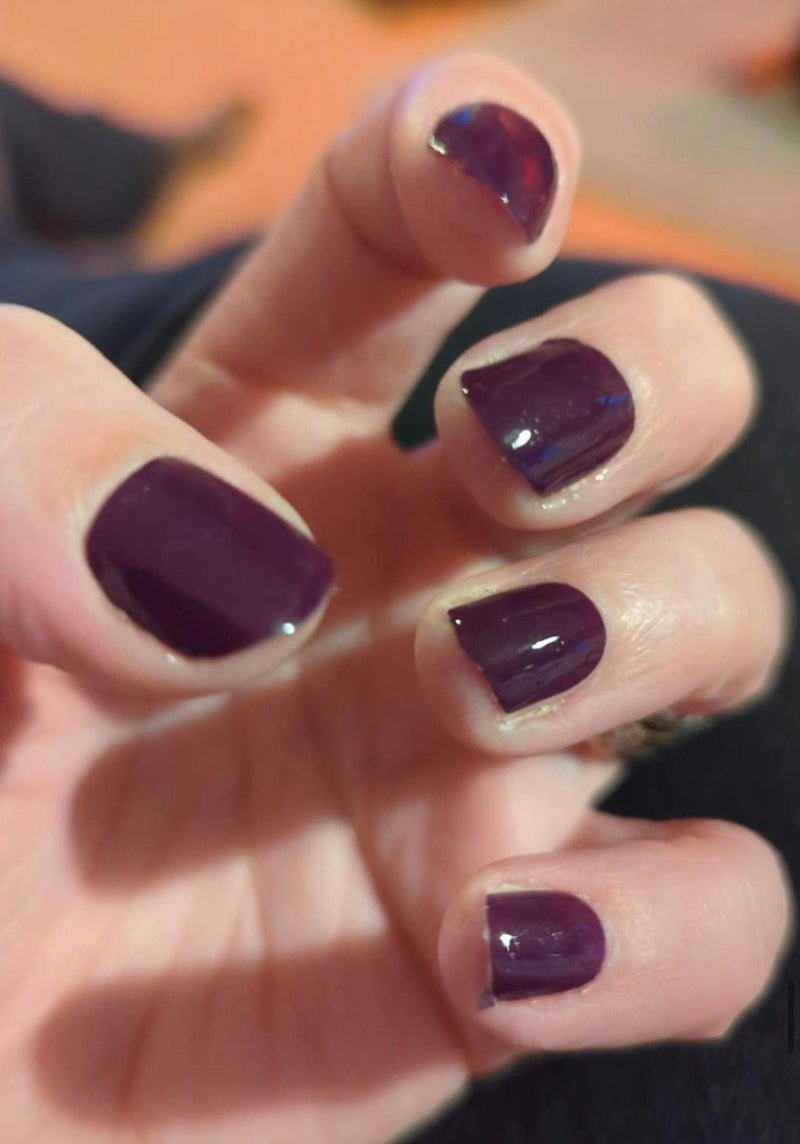 Deep aubergine purple glossy nail wraps on hand showing at-home gel manicure finish