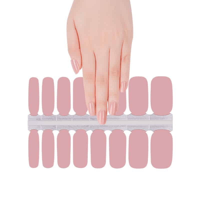 Hand reaching for soft pink peach blossom gel nail wraps displayed on white background