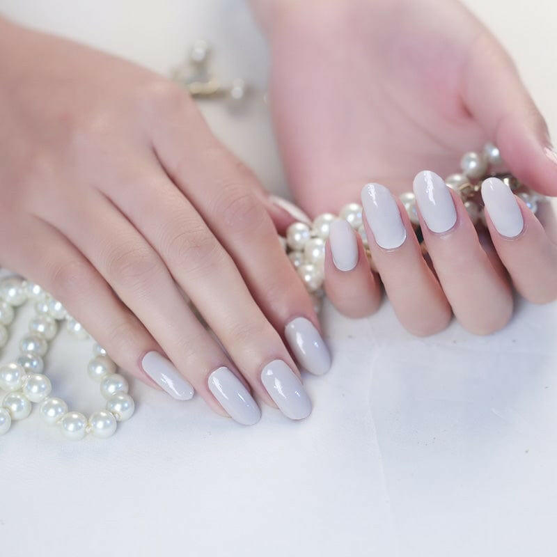 Neutral beige nail wraps on hands with pearl accessories showing classic nude manicure