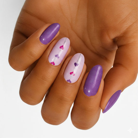 Purple and pink heart pattern nail wraps on hand showing glossy romantic Valentine's manicure design