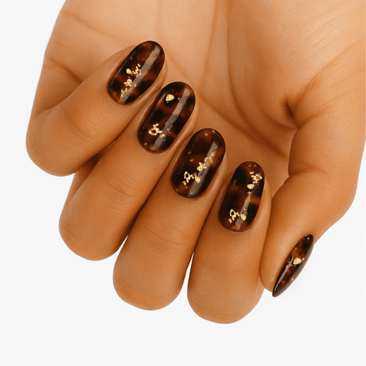 Gold tortoiseshell nail wraps on hand showing metallic foil accent details