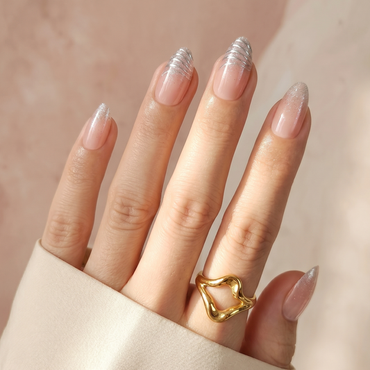 Sheer nude press-on nails with silver glitter French tips, almond shape.