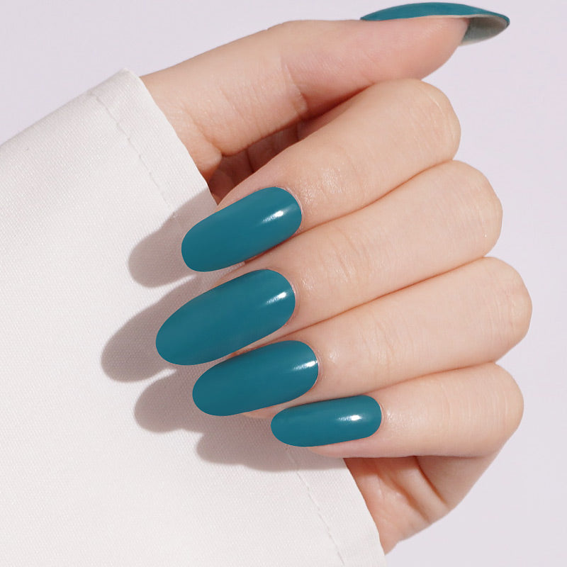 Teal green glossy press-on nails, solid color, oval-shaped medium length manicure.