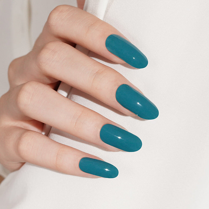 Glossy teal semi-cured gel nail wraps in a solid color on almond-shaped nails.