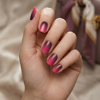 Alternating pink and burgundy ombre gel nails on hand displaying gradient nail art