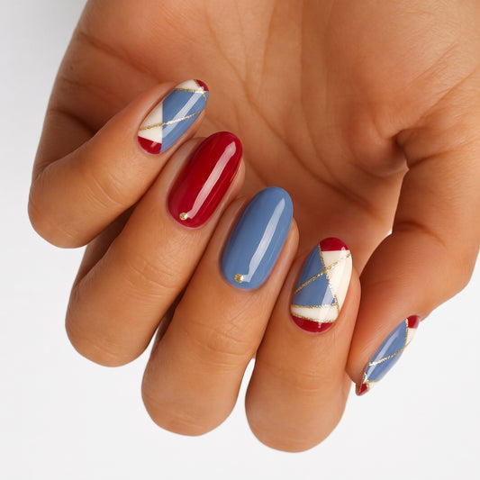 Glossy press-on nails with red, blue, cream color-block geometric design and gold lines