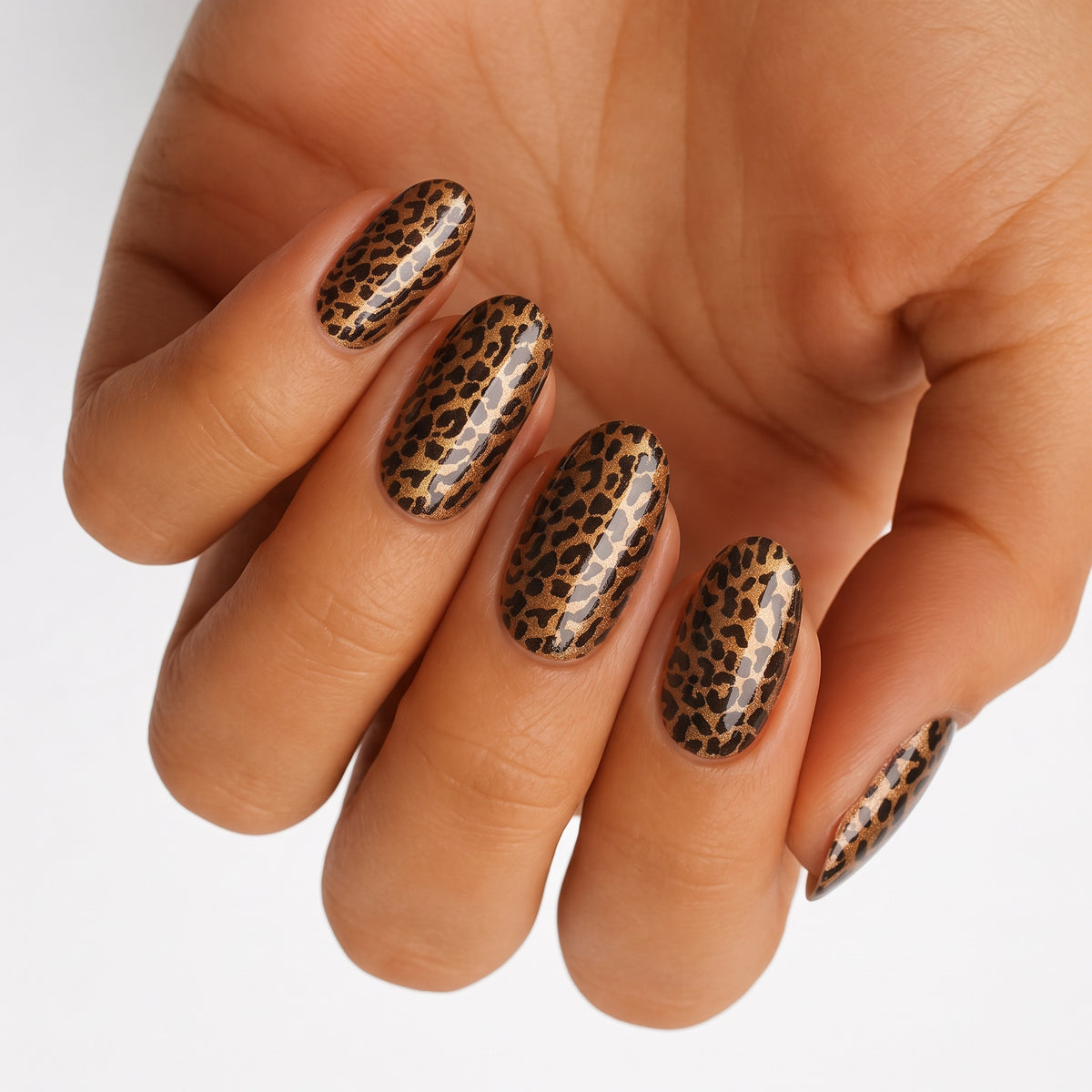Glossy nail wraps in gold and black leopard print on almond-shaped nails