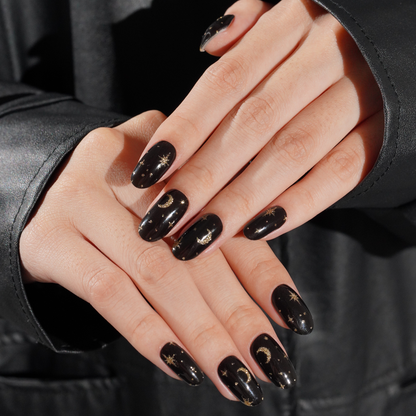 Black glossy press-on nails with gold celestial moon and star design, almond shape.