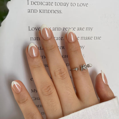 Glossy nude press-on nails with asymmetric white French tips, almond shape