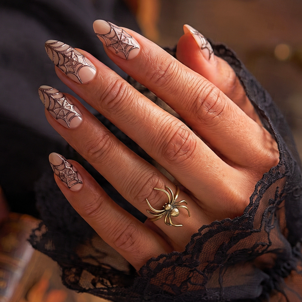 Nude almond soft gel press-ons with metallic bronze spiderweb design on tips