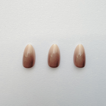 Almond press-on nails with nude-to-brown shimmer ombré gradient finish