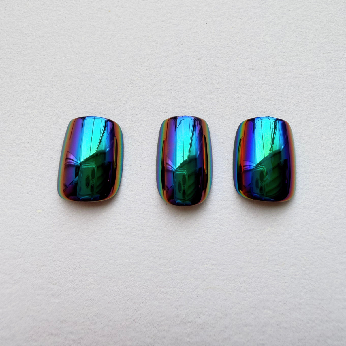 Oil-slick chrome press-on nails with iridescent blue, green and purple mirror finish.