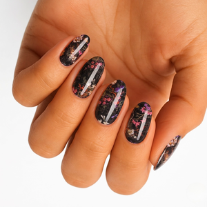 Black nail wraps with pink and purple floral branch design and glossy foil accents