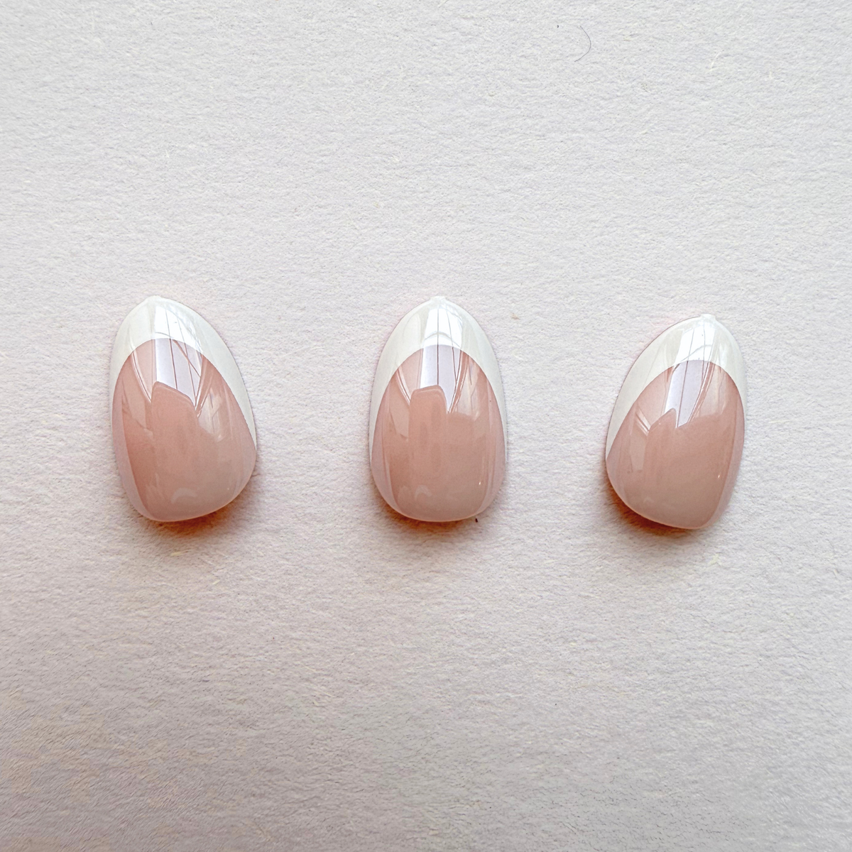 Glossy press-on nails, nude pink base with white diagonal French tips