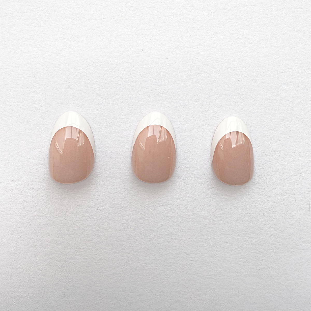 Glossy nude press-on nails with classic white French tips, short round shape