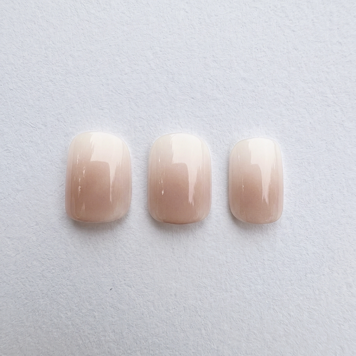 Glossy nude-to-white ombre press-on nails, short rounded square shape.