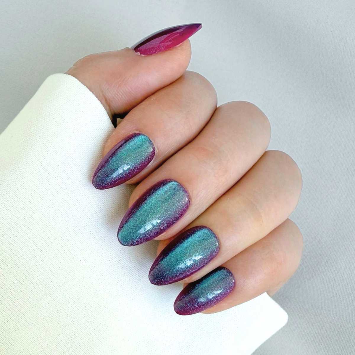 Almond press-on nails, teal-to-purple color-shifting cat-eye chrome finish, glossy semi-cured gel.