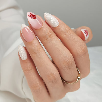 Glossy nude-pink press-on nails with white swirl accents and red gingerbread man design