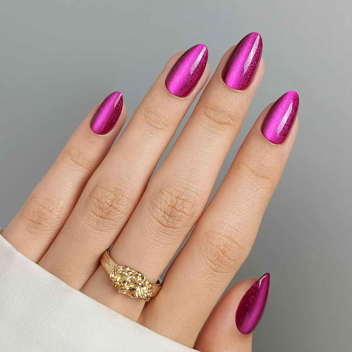 Magenta pink cat-eye chrome press-on nails with metallic shimmer, almond shape