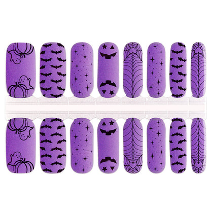 Purple nail wraps with black Halloween prints: bats, ghosts, pumpkins, spiderwebs and stars