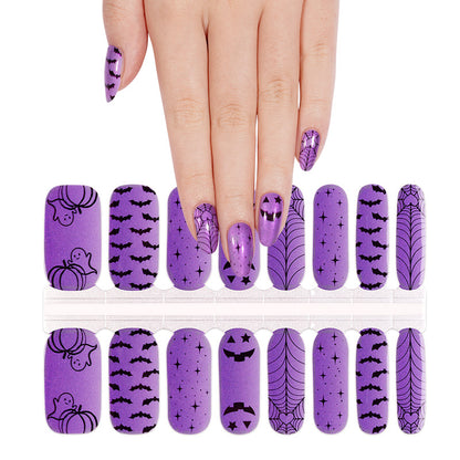 Purple nail wraps with black Halloween prints: bats, spiderwebs, pumpkins, ghosts, jack-o'-lanterns