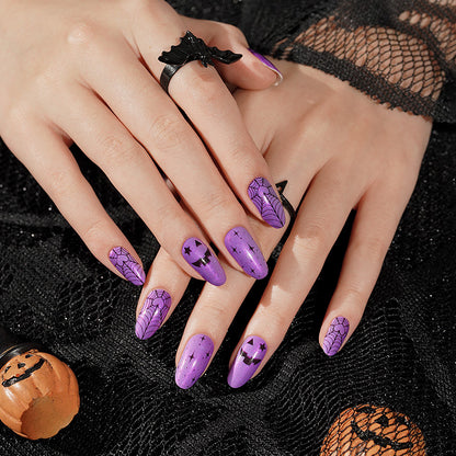 Purple press-on nails with black spiderweb, jack-o'-lantern, and star Halloween designs