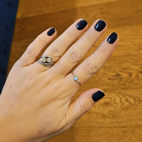 Dark blue nail wraps manicure on hand with rings showing elegant gothic style