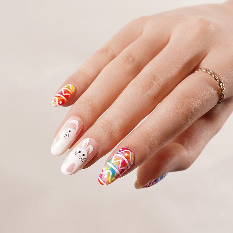 Hand displaying colourful Easter nail wraps with rainbow chevron patterns and white bunny characters