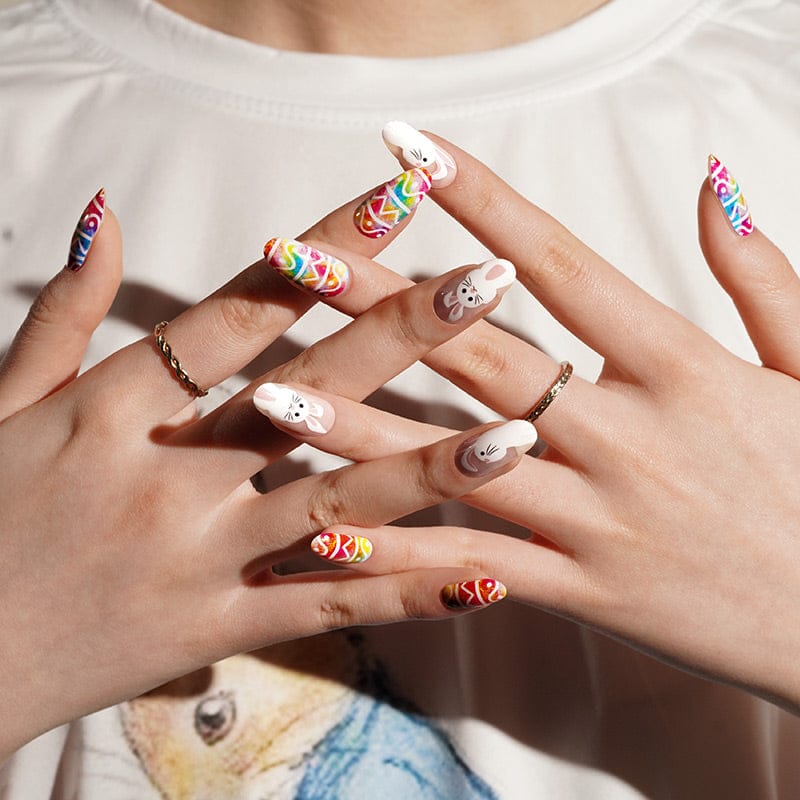 Festive Easter nail wraps on hands showing bright rainbow geometric designs with bunny motifs