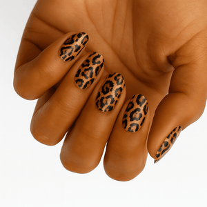 Hand displaying leopard print nail wraps with brown and black spotted pattern