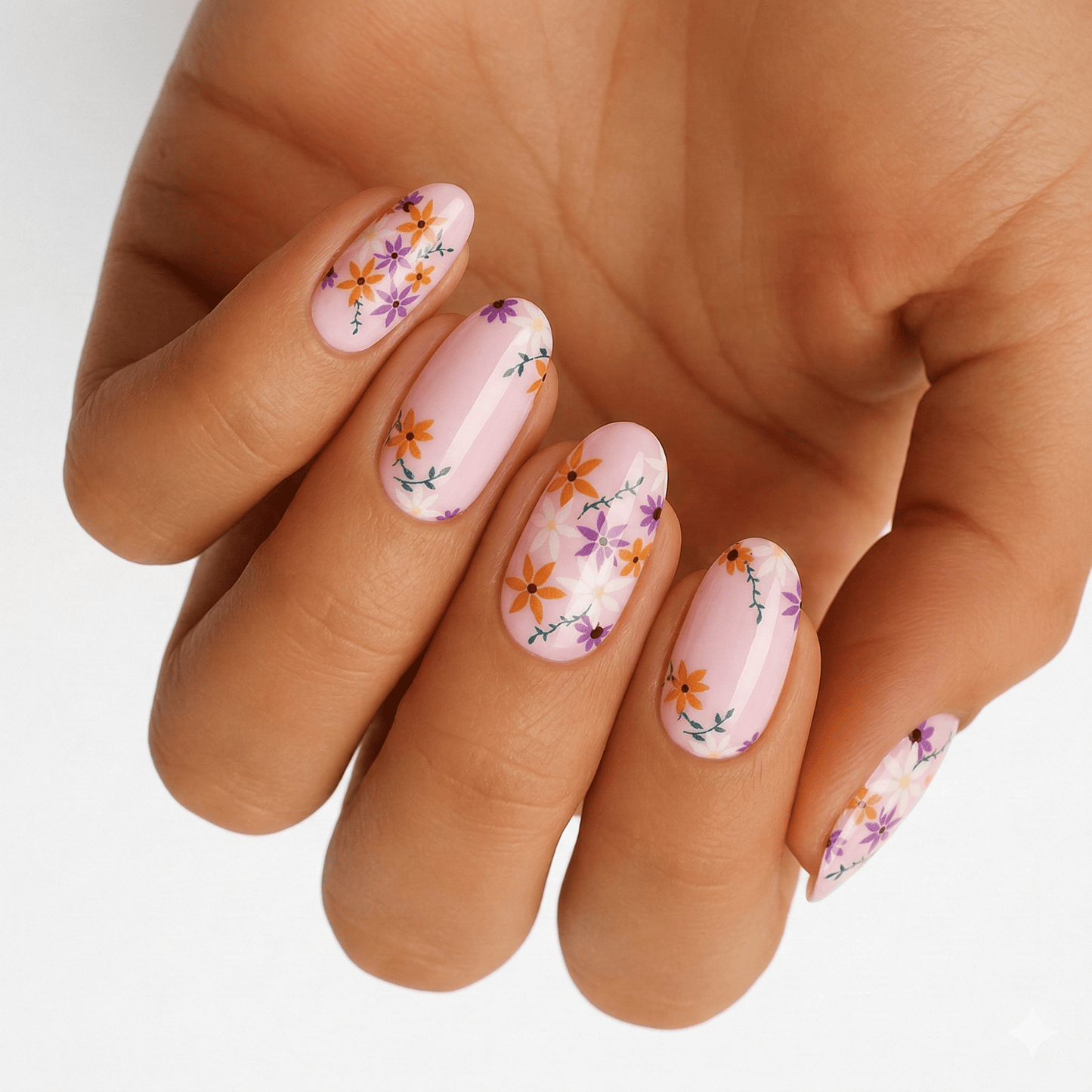 Pink nail wraps with purple pansy floral pattern on hand showing delicate botanical nail art