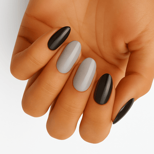 Black and grey glossy oval nail wraps on hand showing monochrome manicure design