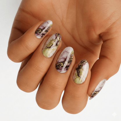 Hand wearing marble effect nail wraps in sage green and mauve with metallic accents