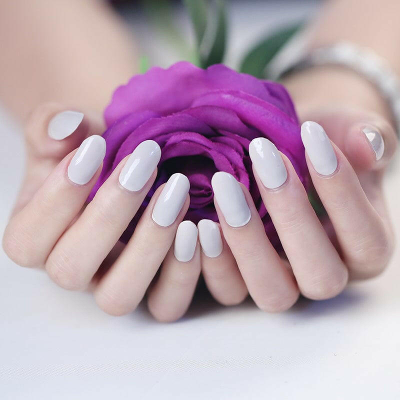 Skinny latte nail wraps on hands cupping purple rose showing natural nude finish