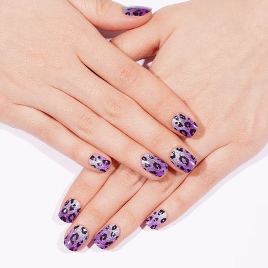 Purple leopard print semi-cured gel nails on hands displaying animal print manicure