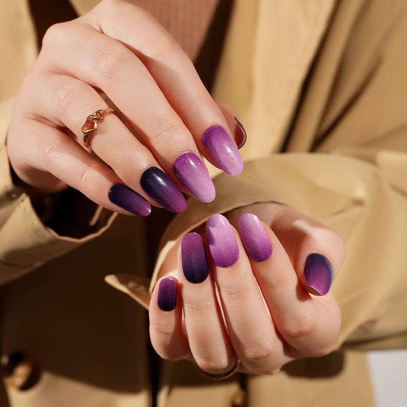 Purple ombre gel nail wraps on hands showing gradient from dark plum to lavender