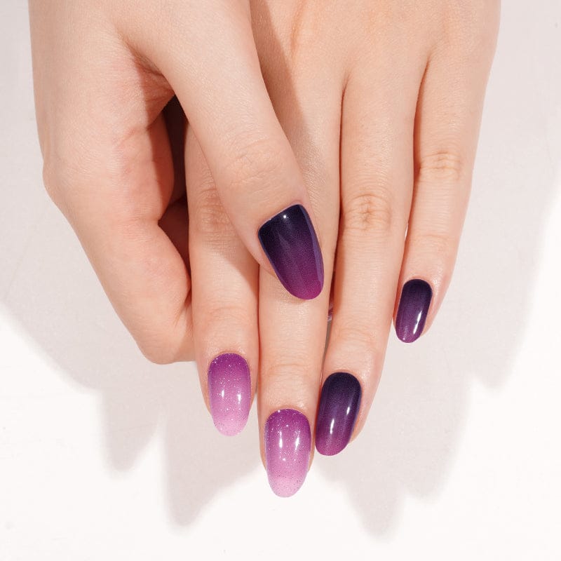 Two hands showing purple gradient gel nails with glossy ombre nail art finish