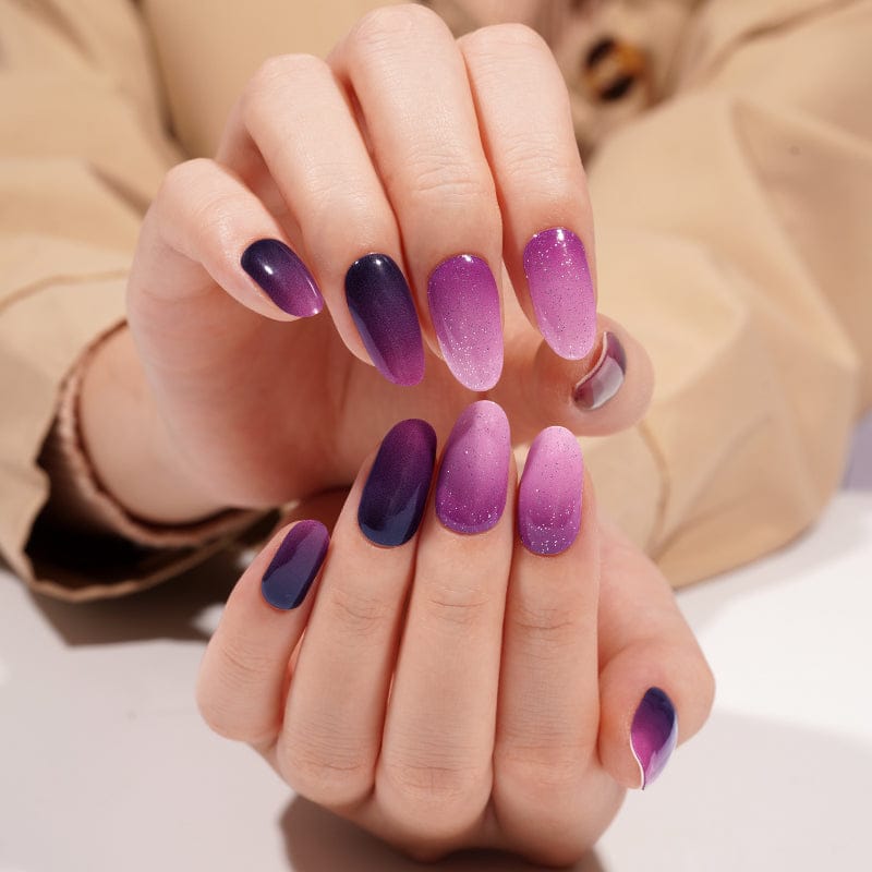 Hands displaying purple gradient gel nails with ombre effect from dark to light shades